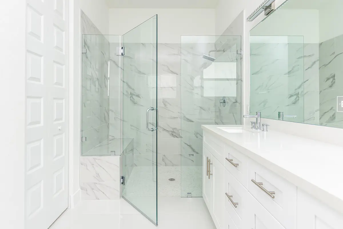 A bathroom with a large walk in shower and white cabinets.