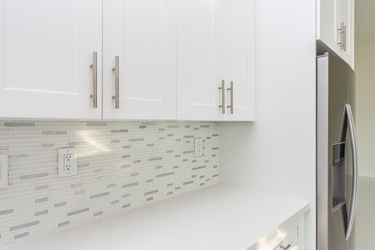 A white kitchen with a tile backsplash and counter.