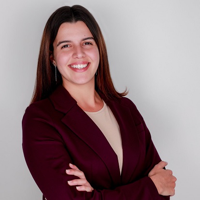 Smiling woman in burgundy blazer, arms crossed.