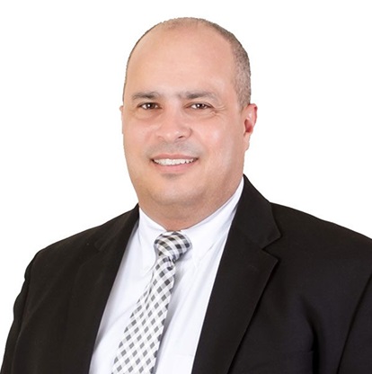 Man in suit smiling against white background.