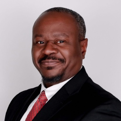 Man in suit with red tie smiling.